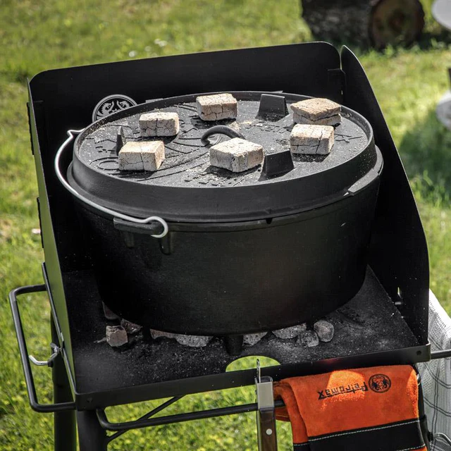 ein Feuertopf mit heißen Briketts auf einem kleinen Feuertisch  auf einer Wiese